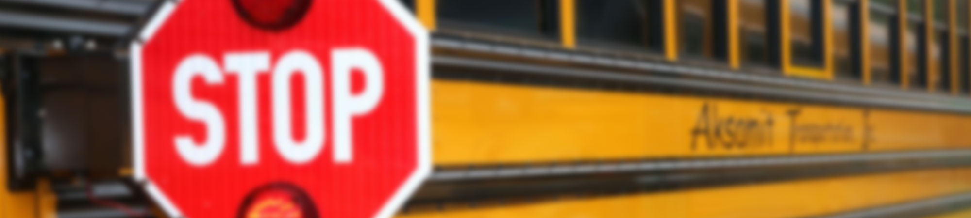 Blurred photo of a yellow school bus with a lighted stop sign on the side